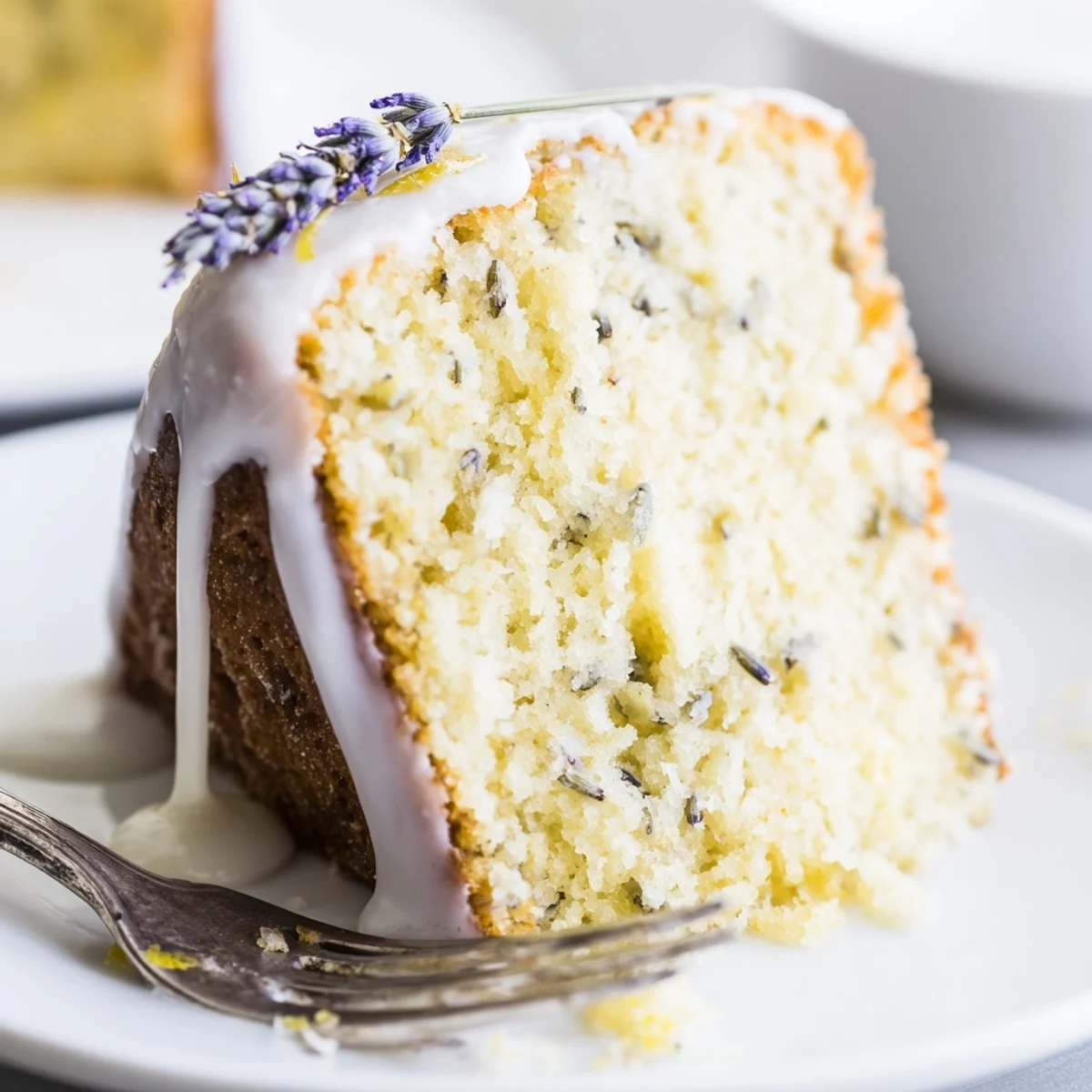 Slice of moist lemon lavender cake revealing tender yellow crumb topped with zesty lemon glaze