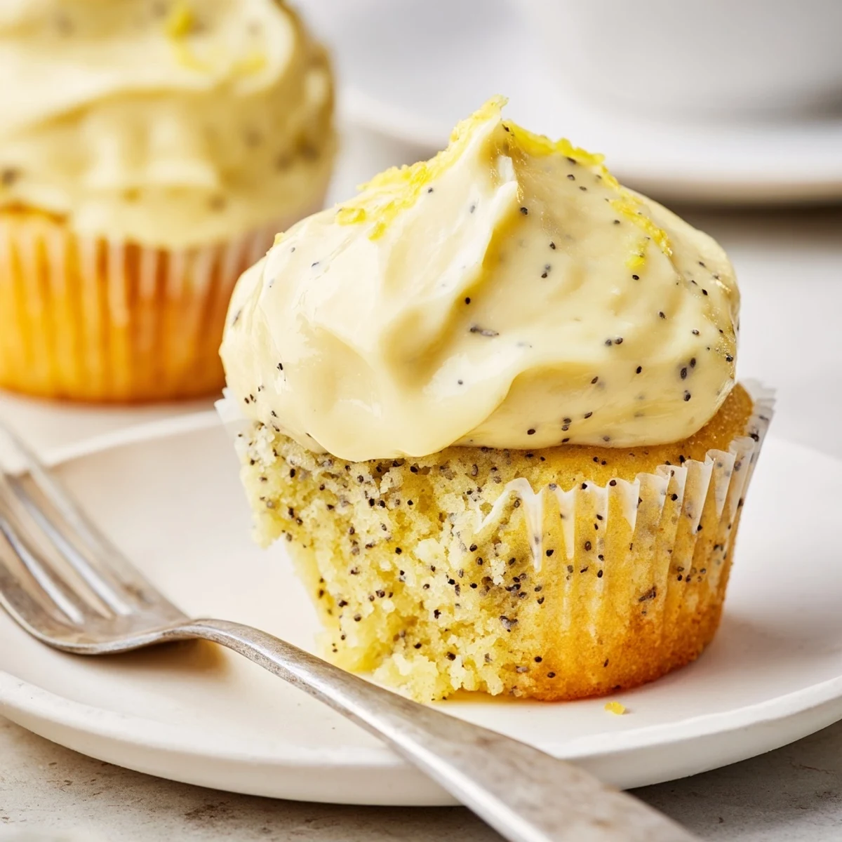 Batch of freshly baked lemon poppy seed cupcakes generously topped with tangy frosting