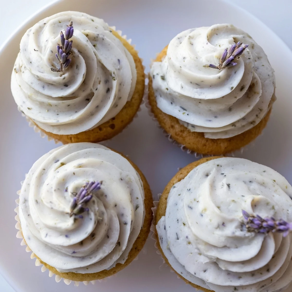 Golden lemon lavender cupcakes topped with creamy white frosting and garnished with fresh lemon zest