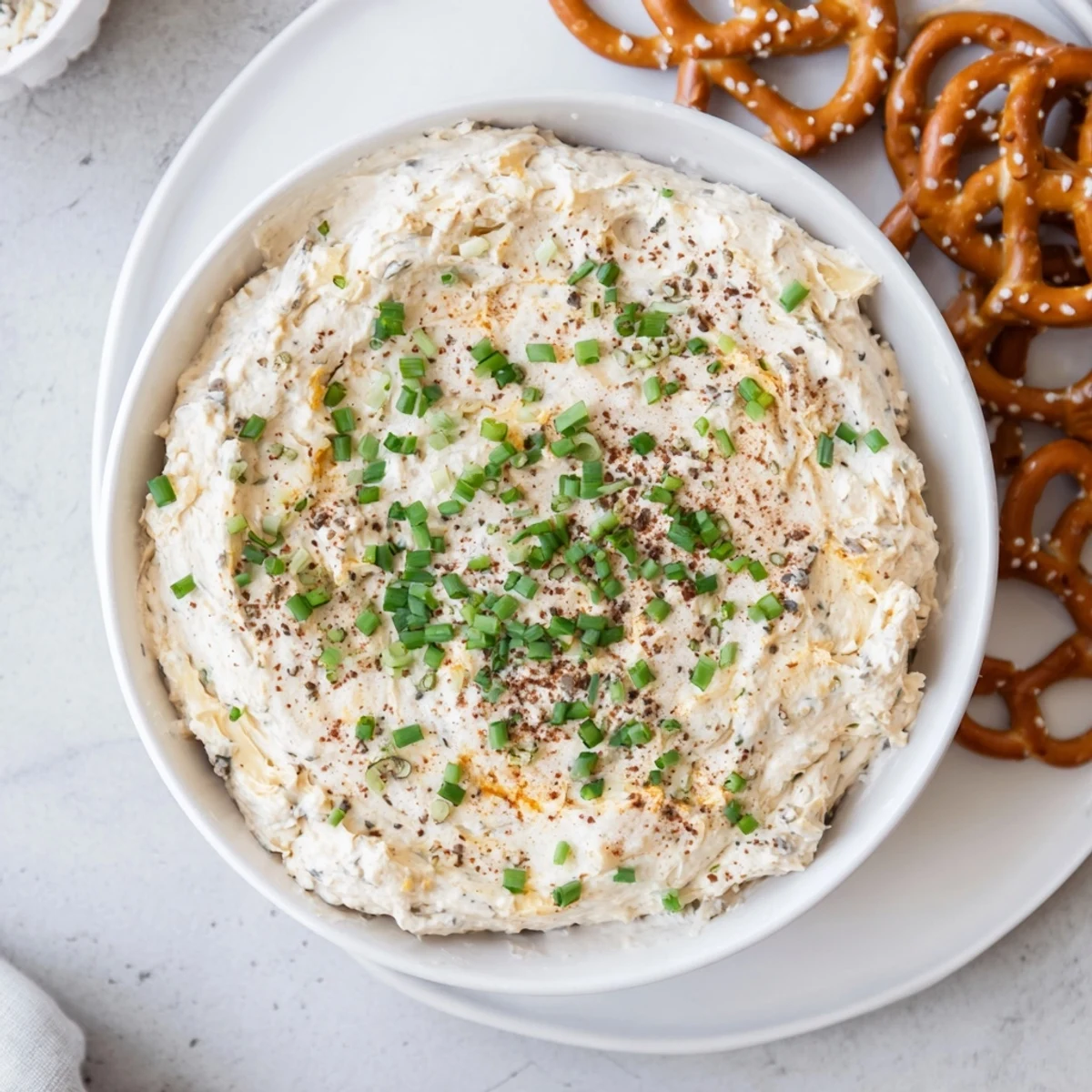 Thick and tangy savory pretzel dip garnished with green onions, perfect for party entertaining
