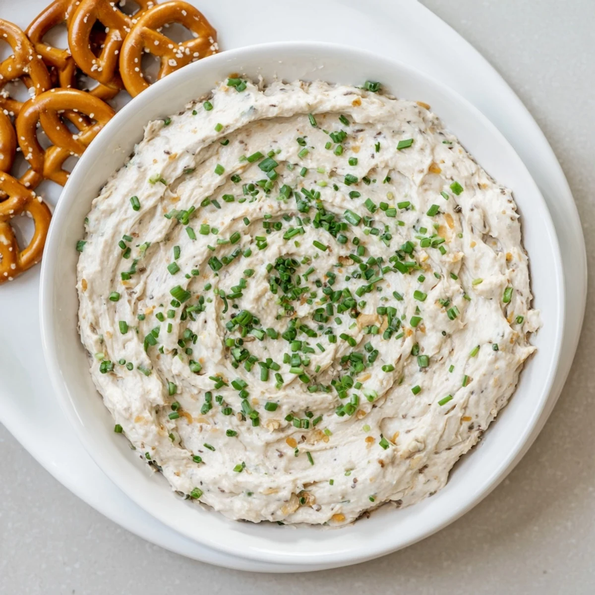 Golden cheddar cheese savory pretzel dip in white bowl with pretzel rods for dipping