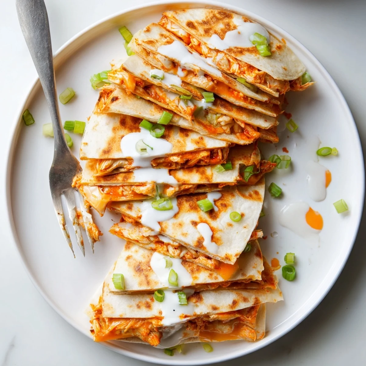 Spicy buffalo chicken quesadillas oozing melted cheese topped with cooling ranch dressing