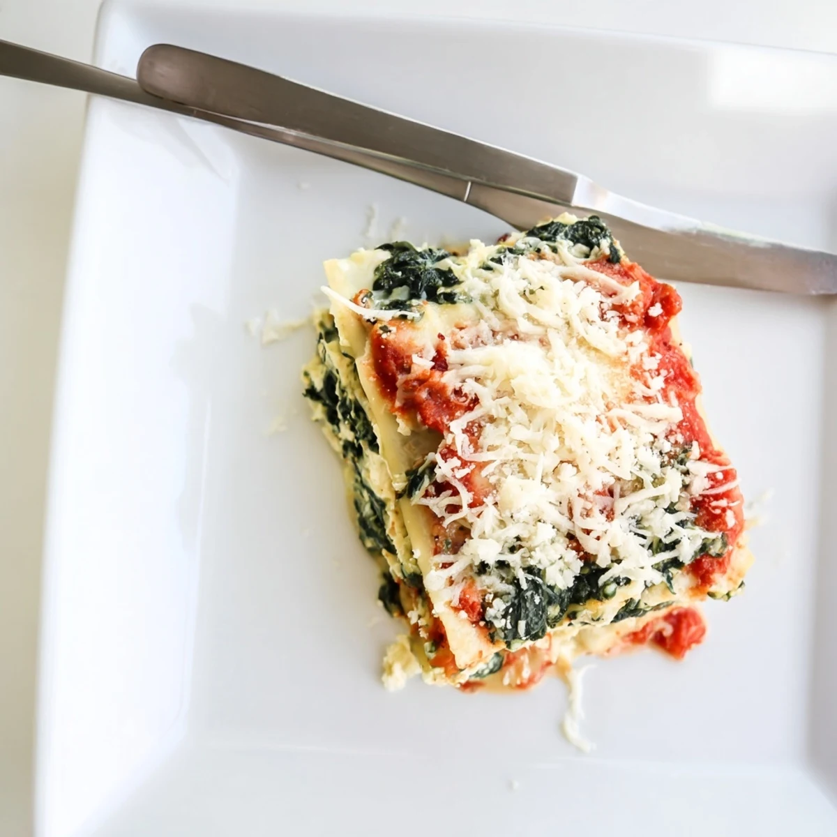 Layered classic spinach ricotta lasagna in glass baking dish showing ricotta spinach and tomato sauce