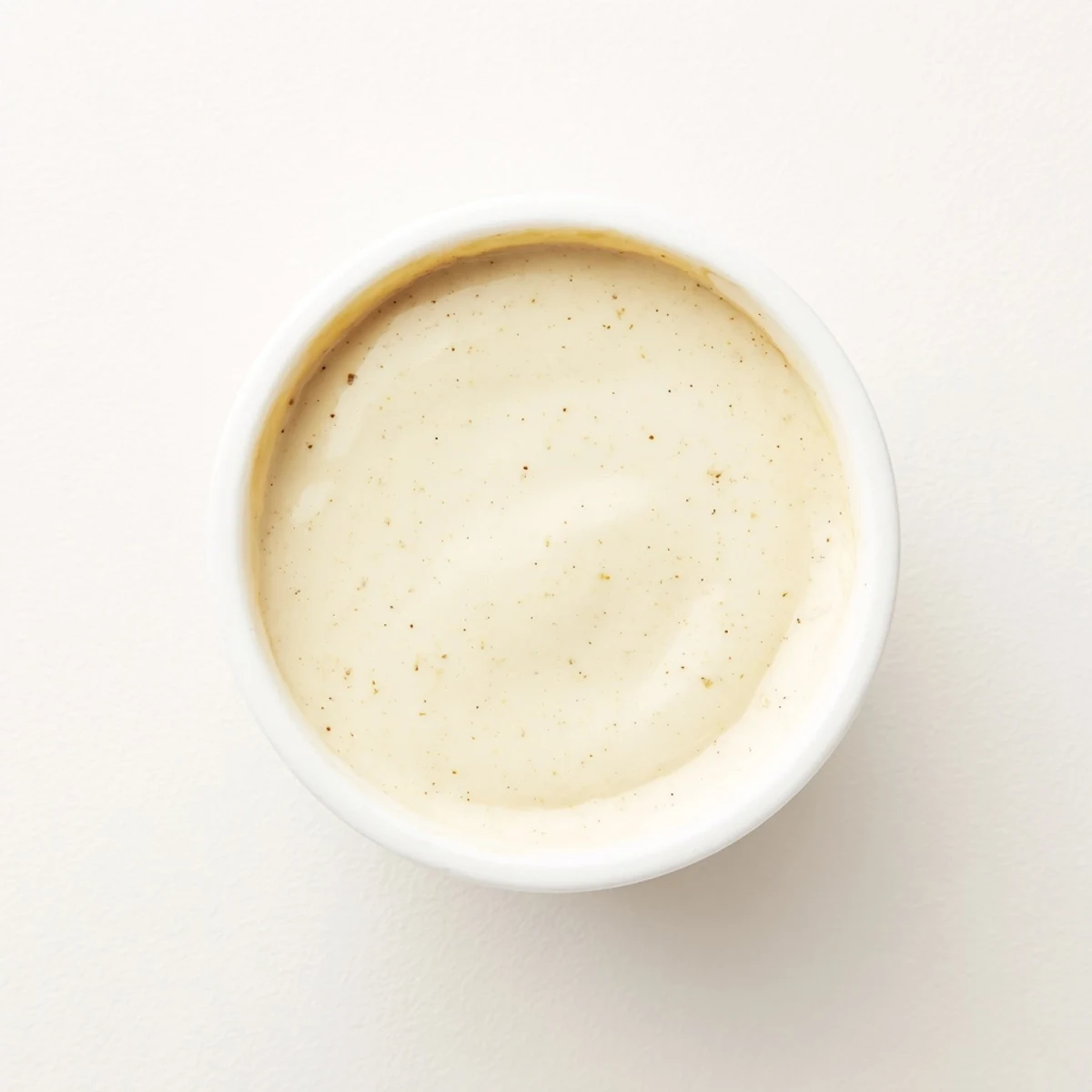 Thick rich shawarma sauce spooned onto中间 eastern wrap with juicy grilled chicken strips peeking out