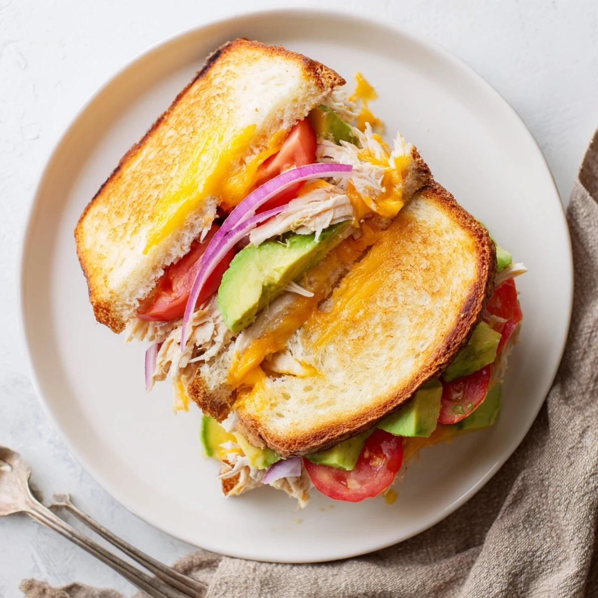 Sliced Chicken Avocado Melt Sandwich revealing layers of tender chicken, creamy green avocado, and melted cheddar cheese
