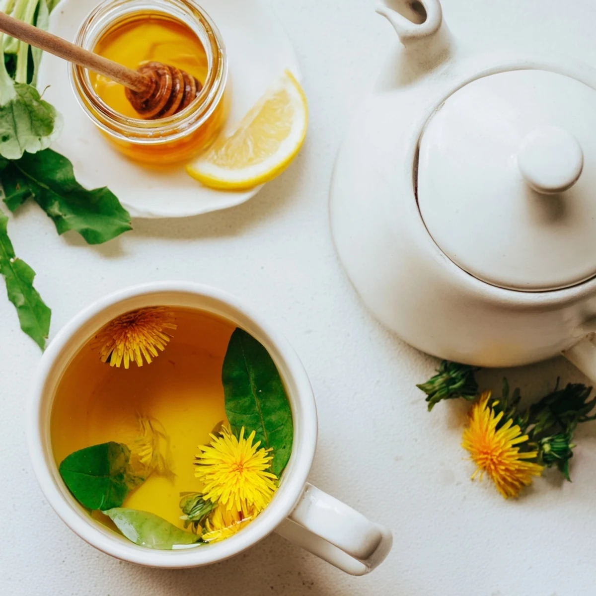 Warm dandelion herbal infusion poured into a clear glass teapot showcasing its light amber color