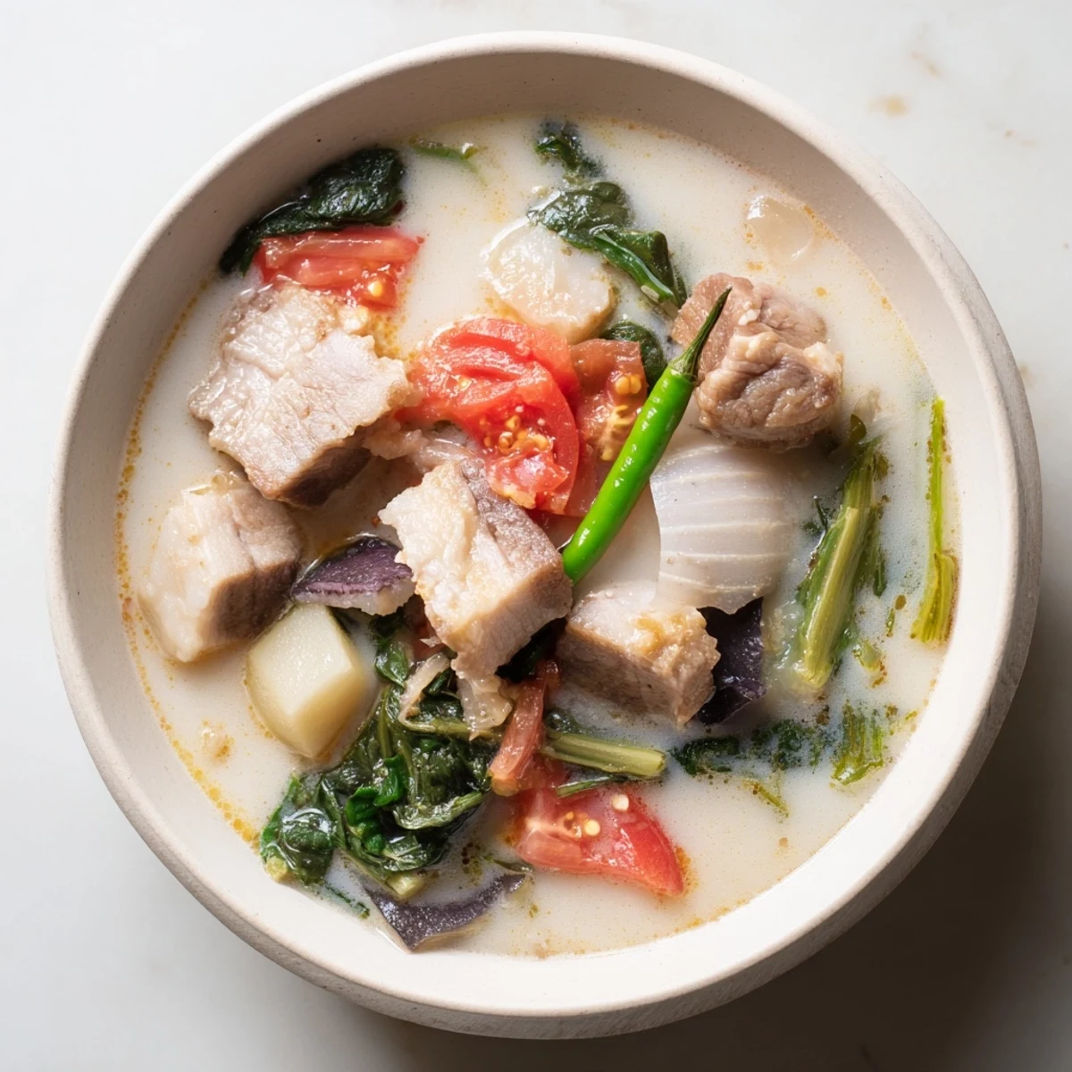 Filipino Sinigang soup served with rice showing vibrant vegetables and rich sour broth