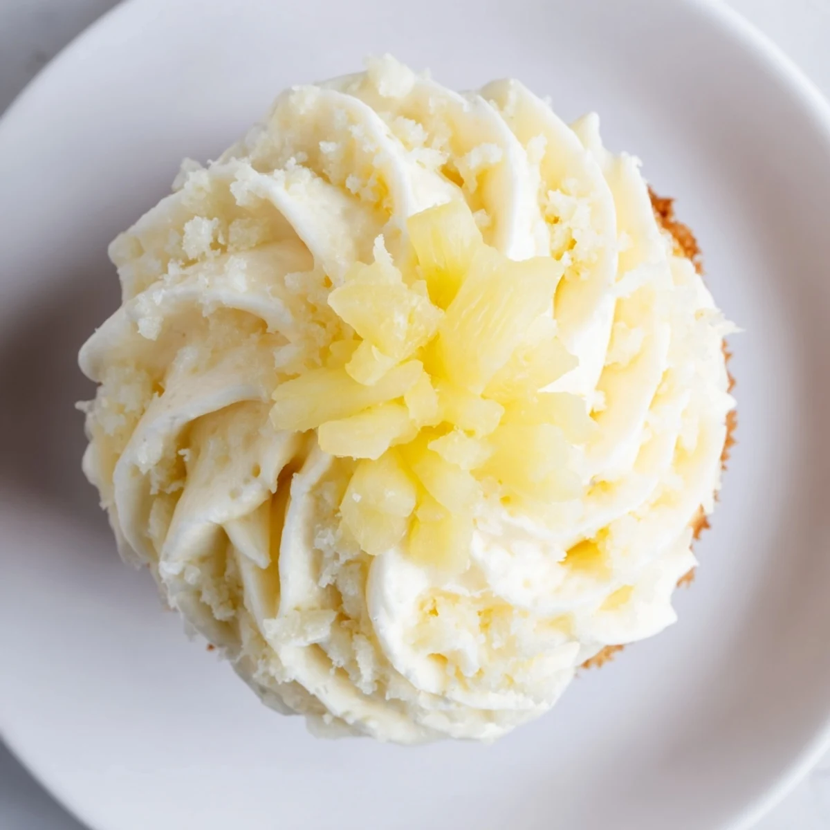 Sunlit plate of Dole Whip Cupcakes recipe garnished with maraschino cherry