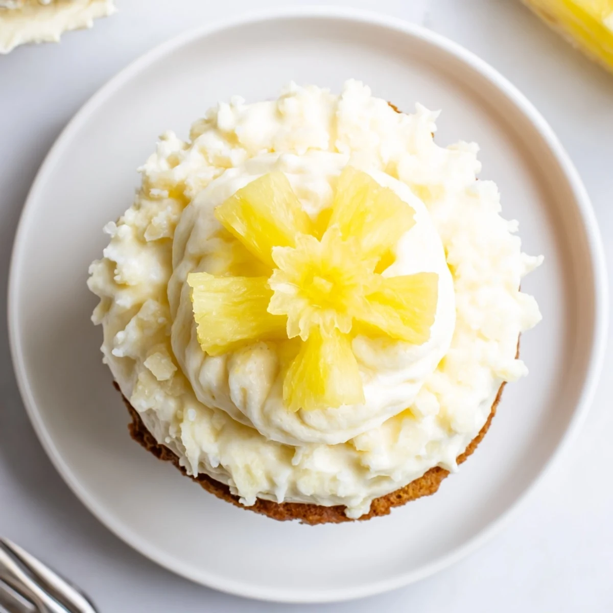 Bite-ready Dole Whip Cupcakes topped with piped tropical frosting and dried pineapple
