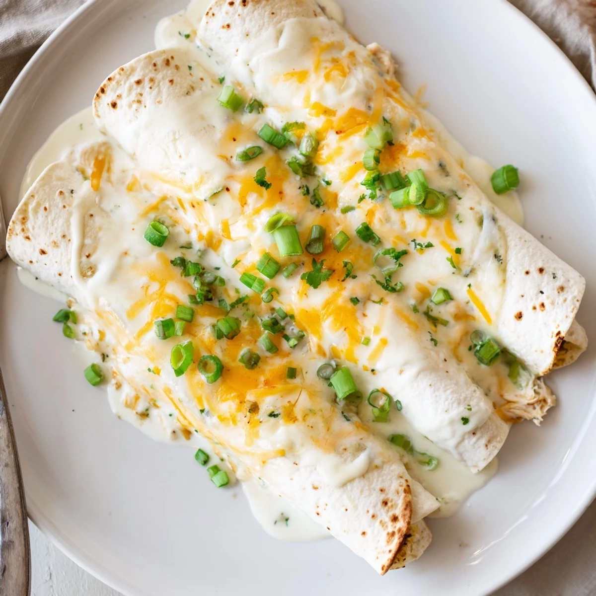 Creamy White Chicken Enchiladas bubbling golden, cheesy edges, cilantro garnish, warm