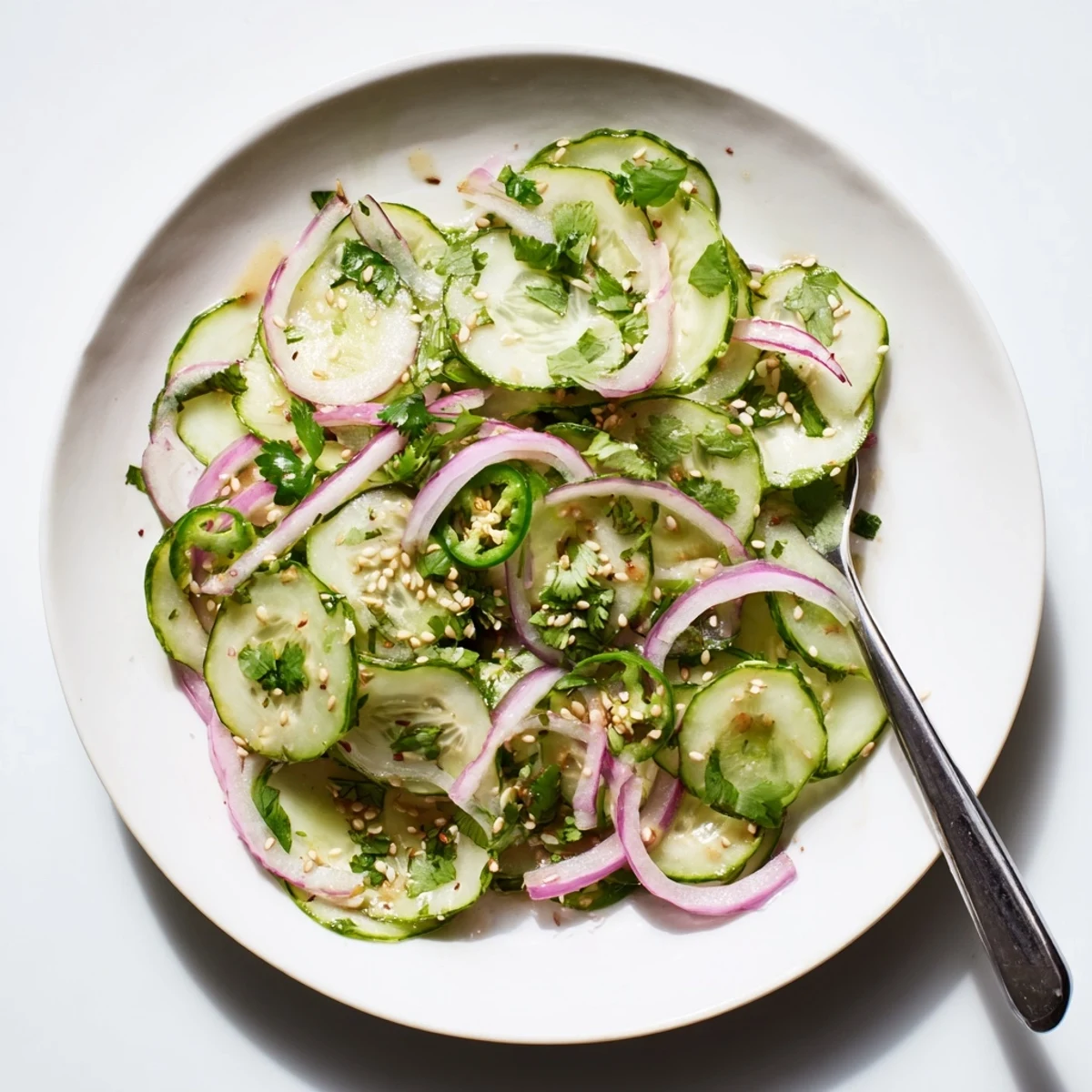 Colorful bowl of Honey Lime Cucumber Salad featuring red onion and fresh cilantro garnish