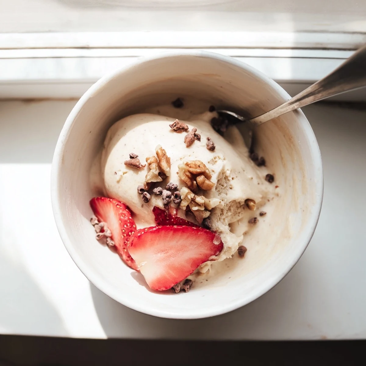 Creamy healthy nice cream recipe scooped into bowls topped with fresh fruit slices and nuts