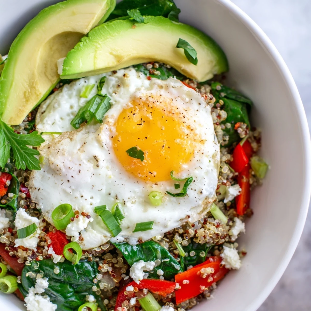 Fluffy quinoa breakfast bowl topped with a golden fried egg and sautéed vegetables