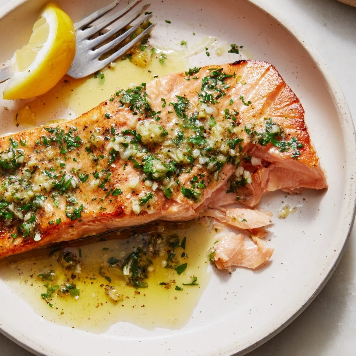 Golden garlic butter salmon fillets glistening with lemon herb sauce on a white plate