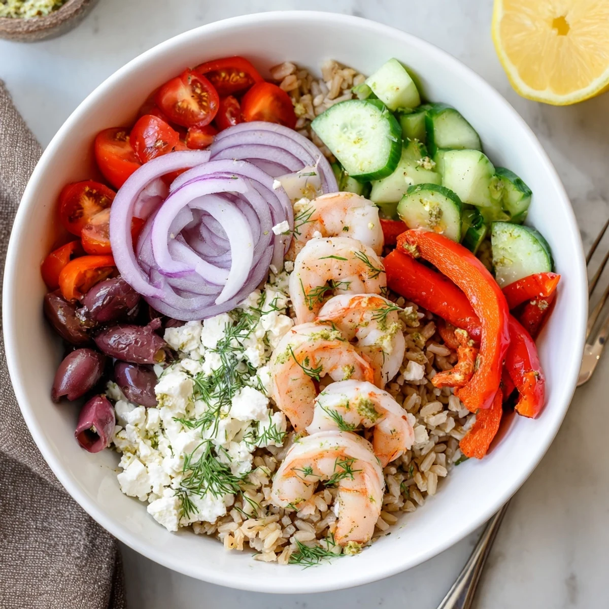 Golden seared shrimp top a colorful Greek Shrimp Mediterranean Bowl with fresh vegetables and crumbled feta cheese