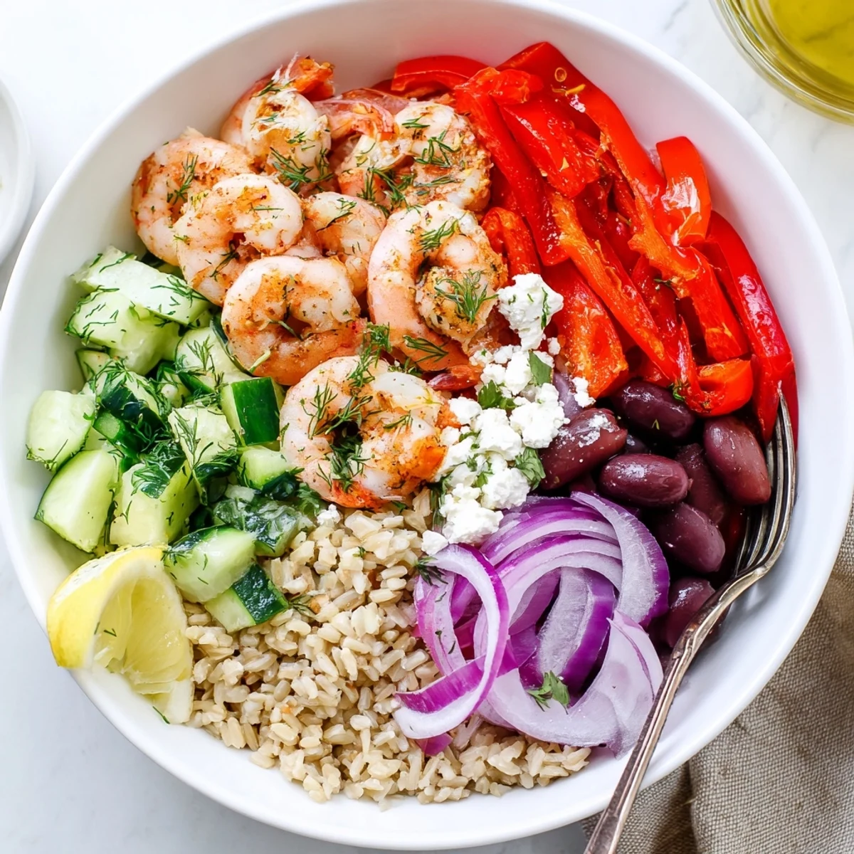 A bright Greek Shrimp Mediterranean Bowl served over brown rice with juicy tomatoes olives and herbs