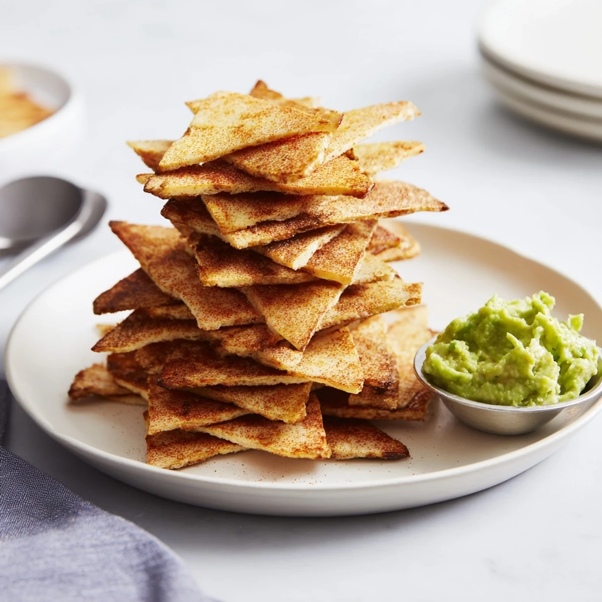 Cottage cheese chips served in a bowl beside fresh guacamole dip
