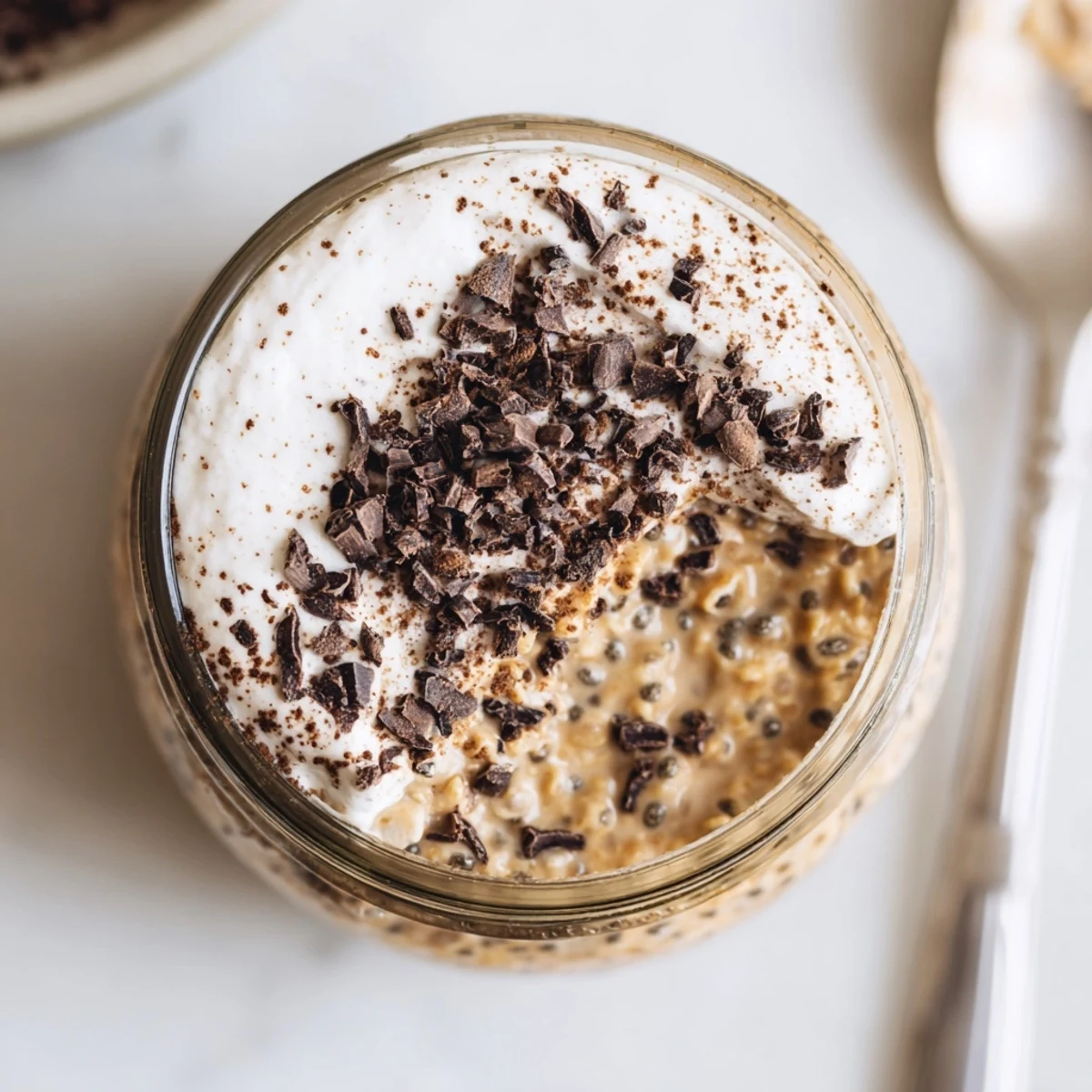 Creamy tiramisu overnight oats layered in a jar with rich mascarpone topping and cocoa dusting