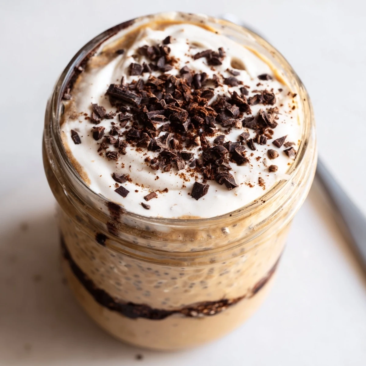 Tiramisu overnight oats served chilled in glass jars topped with dark chocolate shavings